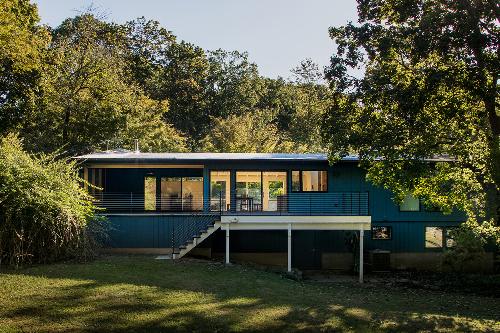 Cette photo montre une façade de maison bleue moderne en bois de taille moyenne et à un étage avec un toit en appentis.