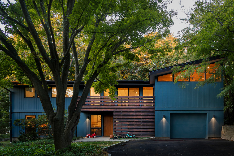 На фото: двухэтажный, деревянный, синий частный загородный дом среднего размера в стиле ретро с односкатной крышей