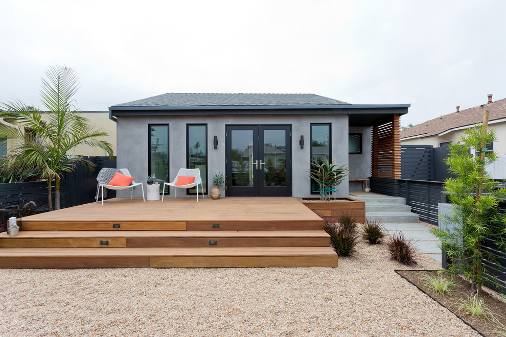 Cette image montre une petite façade de maison grise minimaliste en stuc de plain-pied avec un toit à deux pans et un toit en shingle.