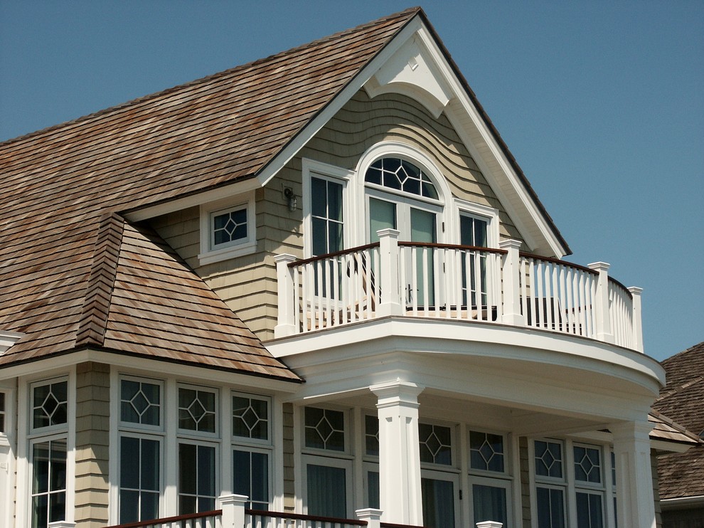 Esempio della villa grande beige stile marinaro a tre piani con rivestimento in legno, tetto a padiglione e copertura a scandole