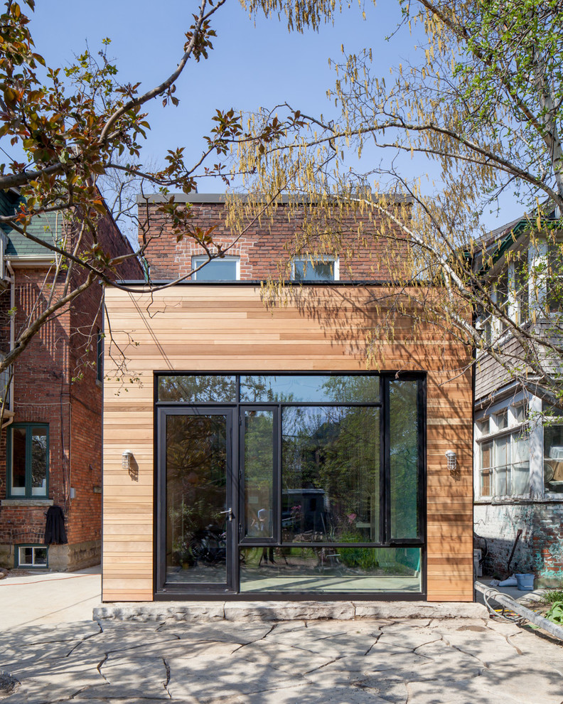 Ejemplo de fachada minimalista de dos plantas con revestimiento de madera y tejado plano