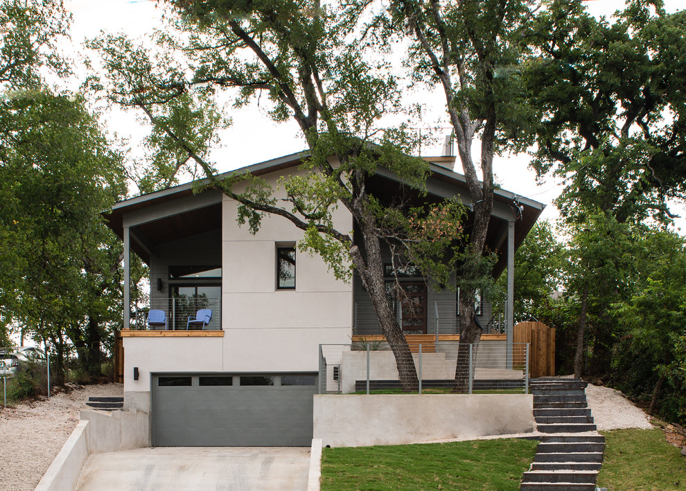 Inspiration pour une grande façade de maison grise design en stuc à un étage avec un toit à deux pans.