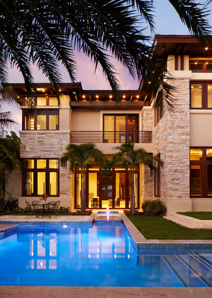 Large contemporary beige two-story stone exterior home idea in Miami with a hip roof