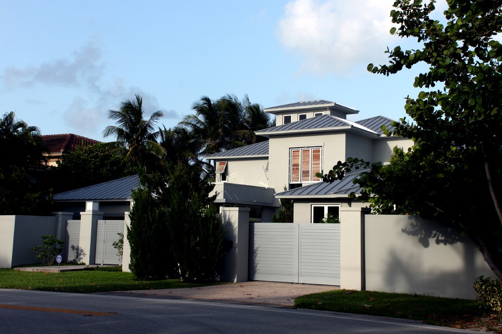 Huge contemporary gray two-story adobe house exterior idea in Miami with a clipped gable roof and a metal roof