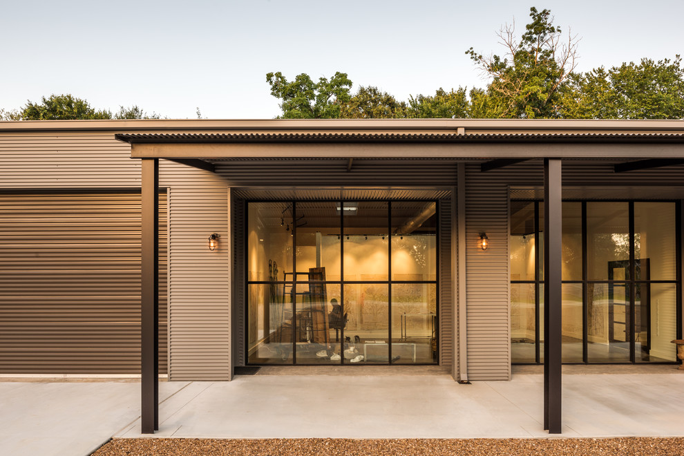 Large and gey urban bungalow house exterior in Houston with metal cladding and a pitched roof.
