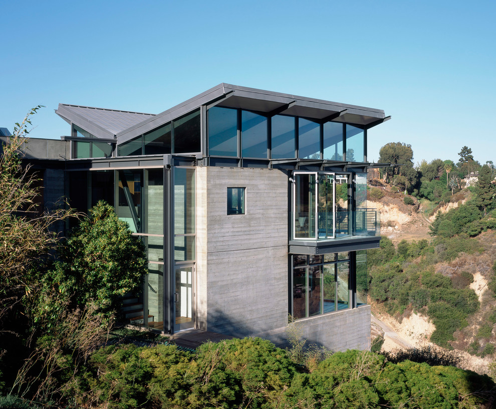 Cette image montre une façade de maison grise design à un étage avec un toit papillon.