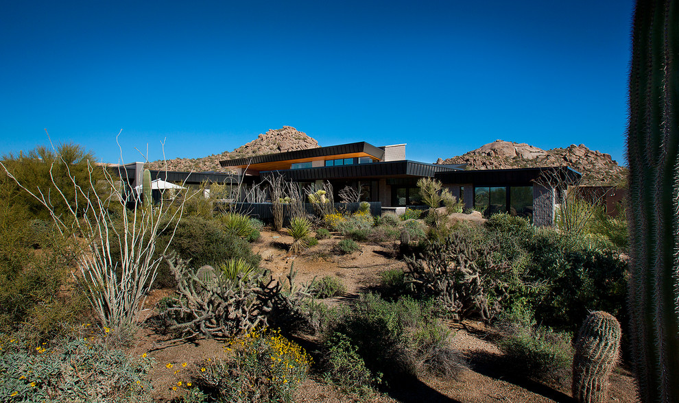 This is an example of an expansive and gey contemporary bungalow house exterior in Phoenix with mixed cladding.