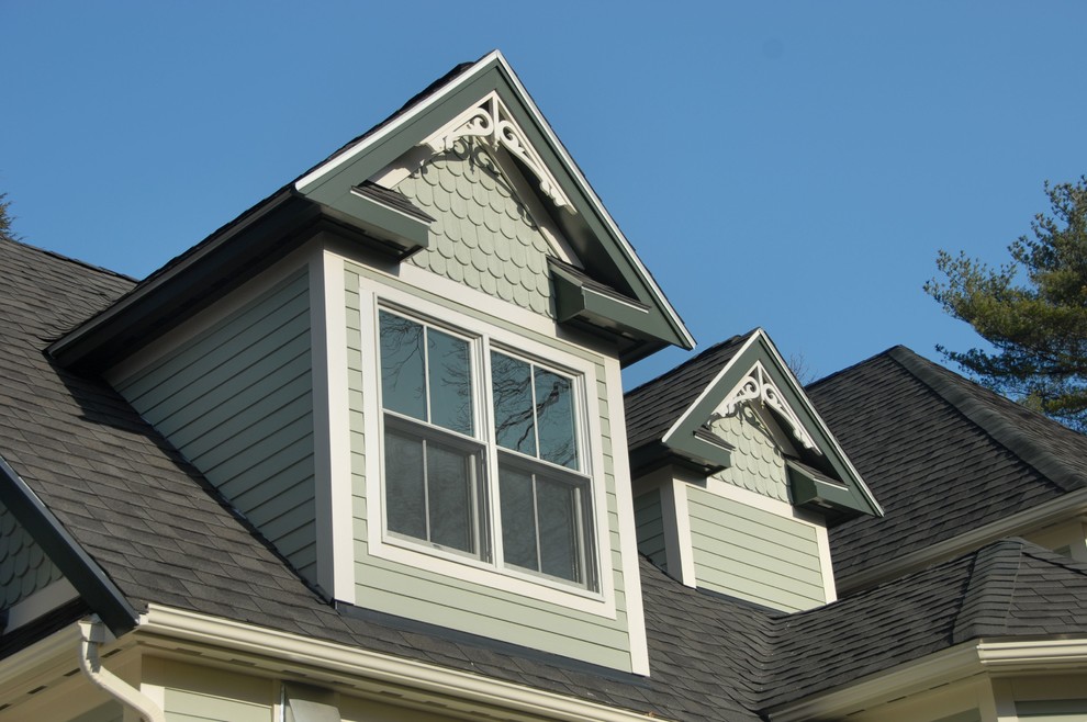 Esempio della facciata di una casa verde classica a due piani con rivestimento in legno e tetto a capanna