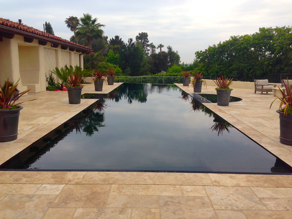 Geräumiger Mediterraner Infinity-Pool hinter dem Haus in rechteckiger Form mit Wasserspiel und Natursteinplatten in San Diego