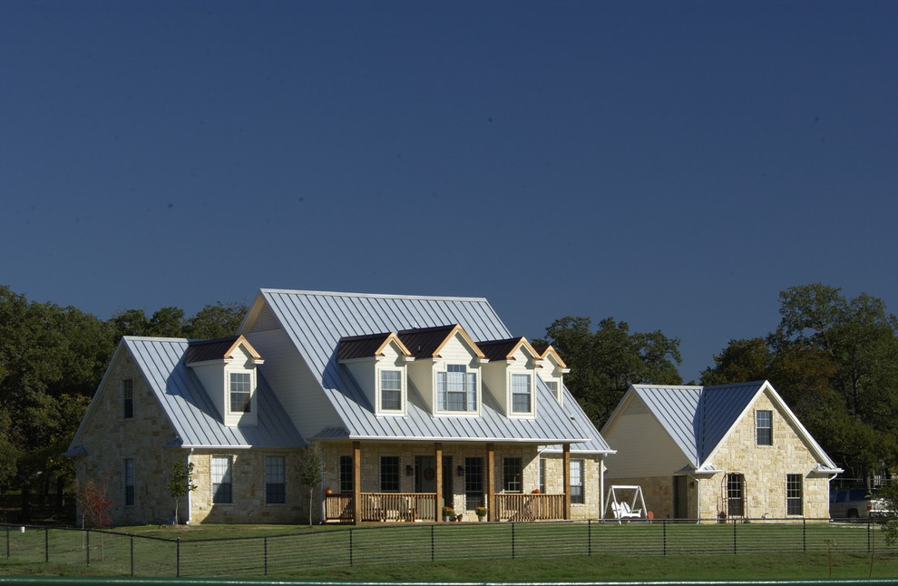 Imagen de fachada de casa beige de estilo de casa de campo grande de dos plantas con revestimiento de piedra, tejado a dos aguas y tejado de metal