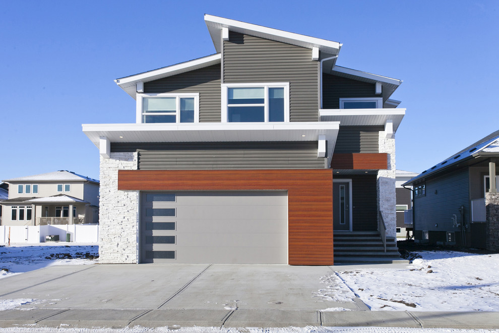 Cette image montre une façade de maison grise traditionnelle de taille moyenne et à un étage avec un revêtement en vinyle et un toit à croupette.