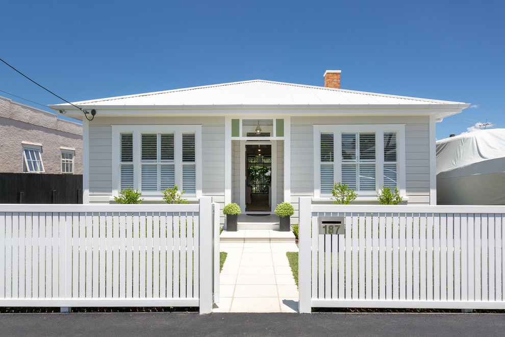 Inspiration for a large transitional white one-story wood house exterior remodel in Auckland with a metal roof and a hip roof