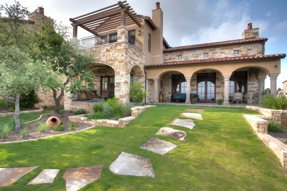 Zweistöckiges Mediterranes Haus mit Steinfassade und beiger Fassadenfarbe in Austin