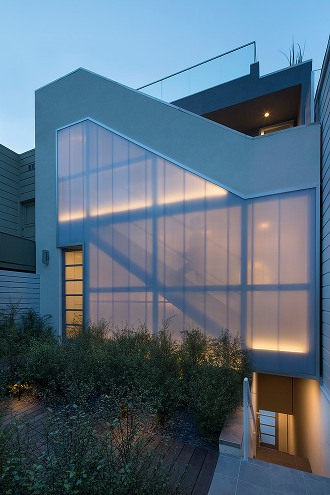 Diseño de fachada gris contemporánea de tres plantas con revestimientos combinados