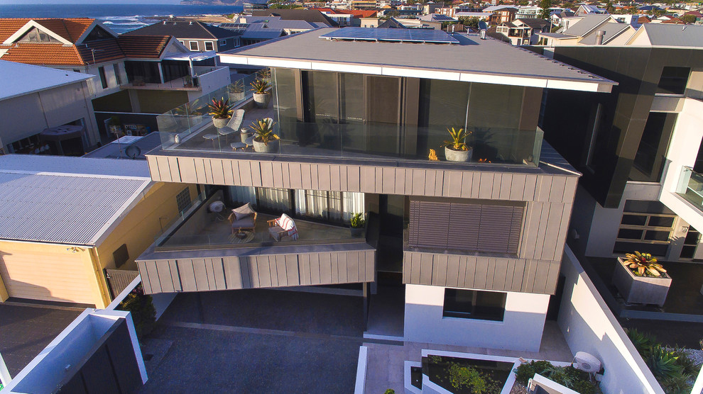 На фото: большой, трехэтажный, серый дом в современном стиле с облицовкой из металла и плоской крышей