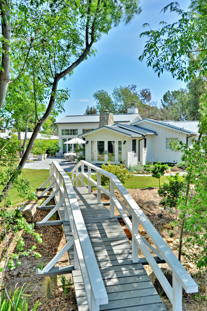 Exemple d'une façade de maison blanche nature en bois de taille moyenne et de plain-pied avec un toit à deux pans et un toit en métal.