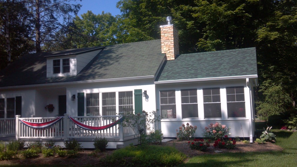 На фото: маленький, двухэтажный, деревянный, белый дом в стиле кантри с двускатной крышей для на участке и в саду