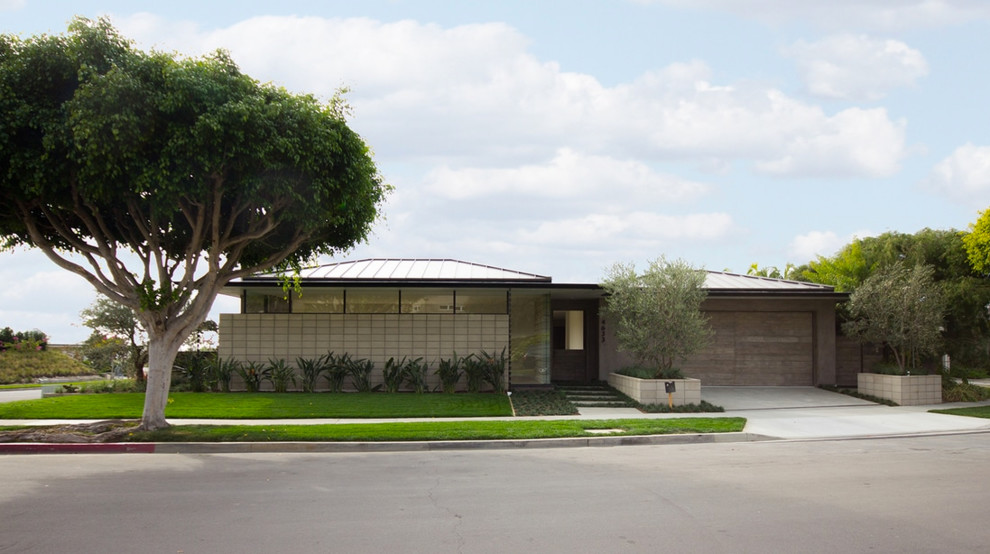 Cette image montre une façade de maison grise vintage en béton de plain-pied avec un toit à quatre pans et un toit en métal.