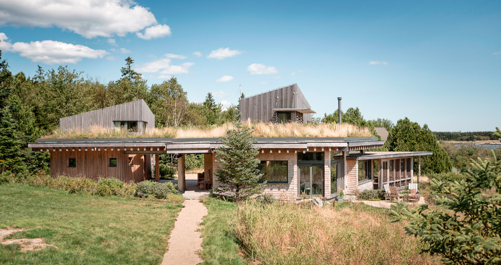 Foto de fachada de casa gris escandinava de tamaño medio de dos plantas con revestimiento de madera, tejado plano y techo verde
