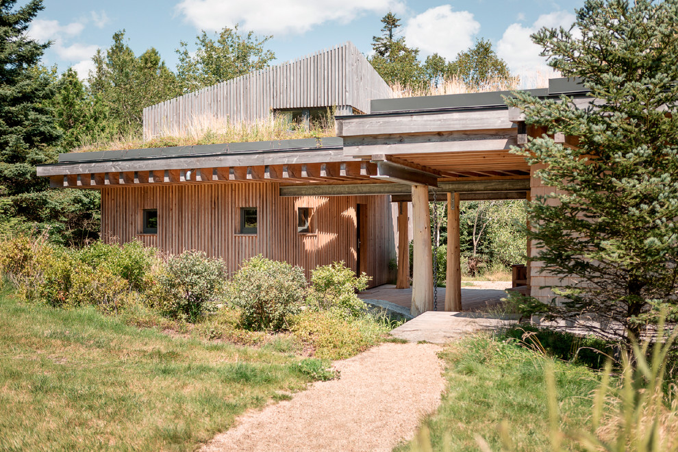 Cette photo montre une façade de maison marron tendance en bois à un étage avec un toit en appentis et un toit végétal.