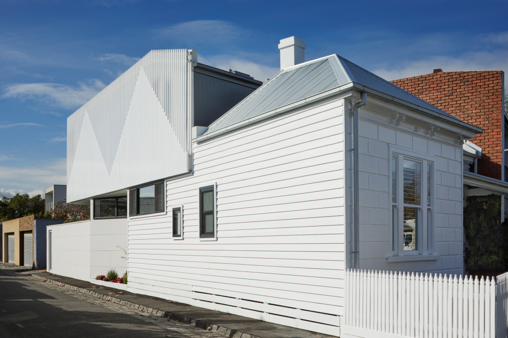 Immagine della villa piccola bianca contemporanea a due piani con rivestimento in metallo, tetto piano e copertura in metallo o lamiera