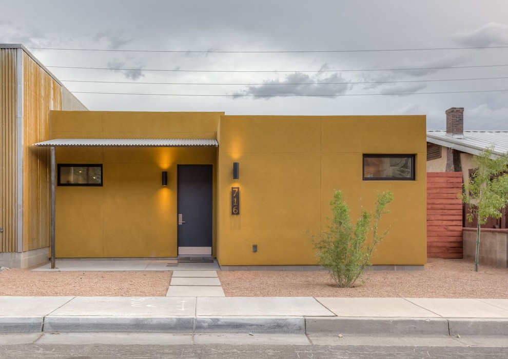 Inspiration for a small and yellow midcentury bungalow render house exterior in Albuquerque with a flat roof.