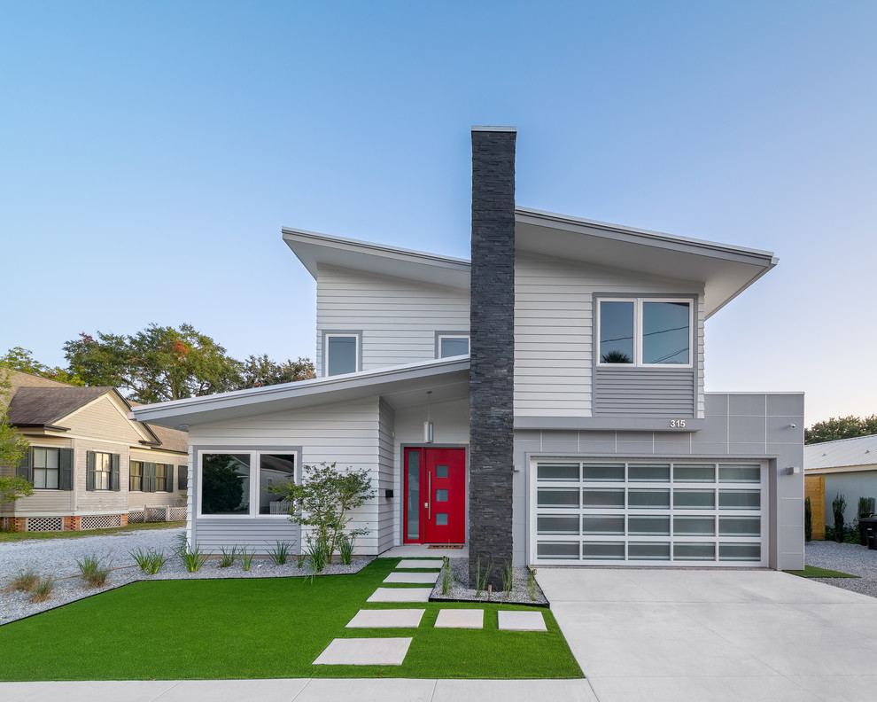 Inspiration pour une façade de maison grise design en panneau de béton fibré de taille moyenne et à un étage avec un toit en appentis et un toit en métal.