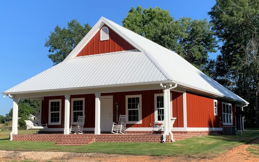 Foto de fachada de casa roja de estilo de casa de campo pequeña de una planta con revestimiento de aglomerado de cemento, tejado a dos aguas y tejado de metal