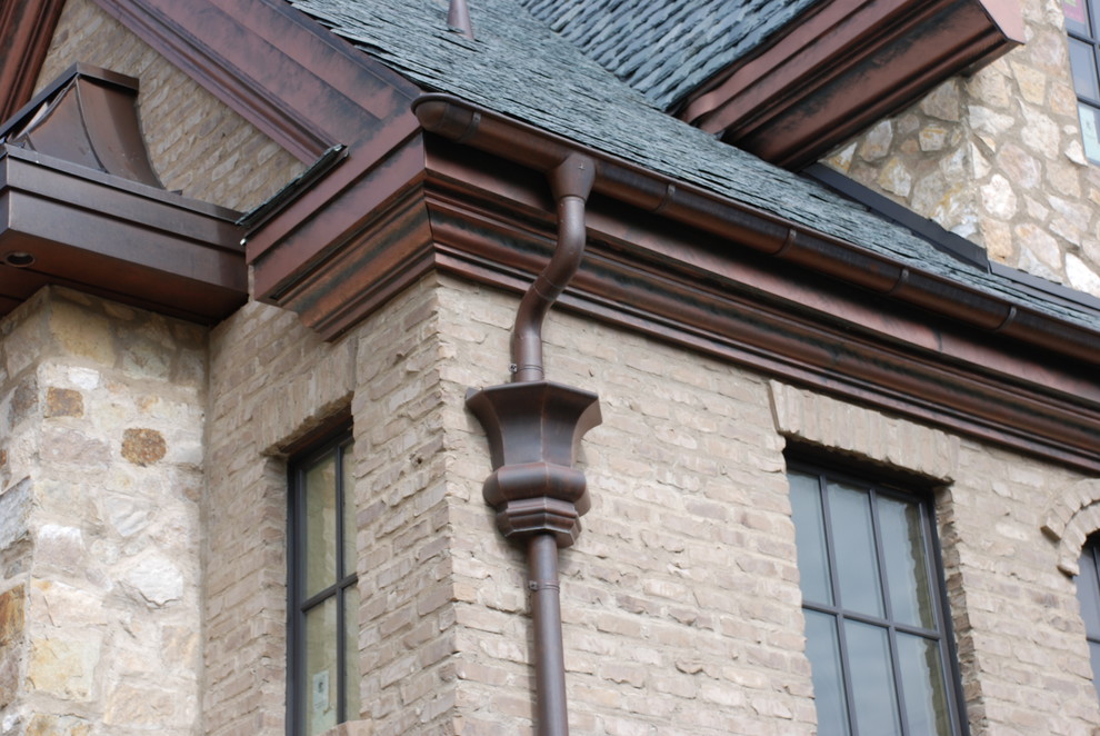 Пример оригинального дизайна: огромный, коричневый частный загородный дом в стиле кантри с разными уровнями, облицовкой из камня, полувальмовой крышей и крышей из гибкой черепицы
