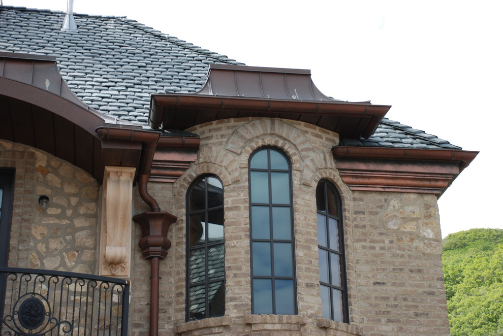 Immagine della villa ampia marrone american style a piani sfalsati con rivestimento in pietra, falda a timpano e copertura a scandole