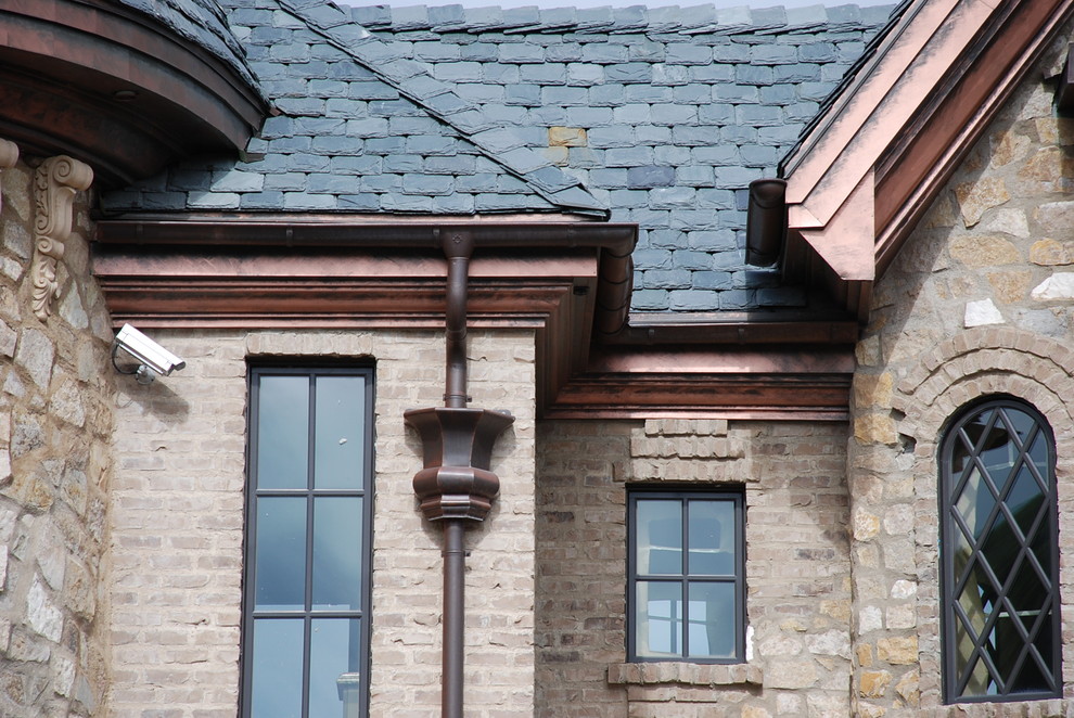 Bild på ett mycket stort amerikanskt brunt hus i flera nivåer, med halvvalmat sadeltak och tak i shingel