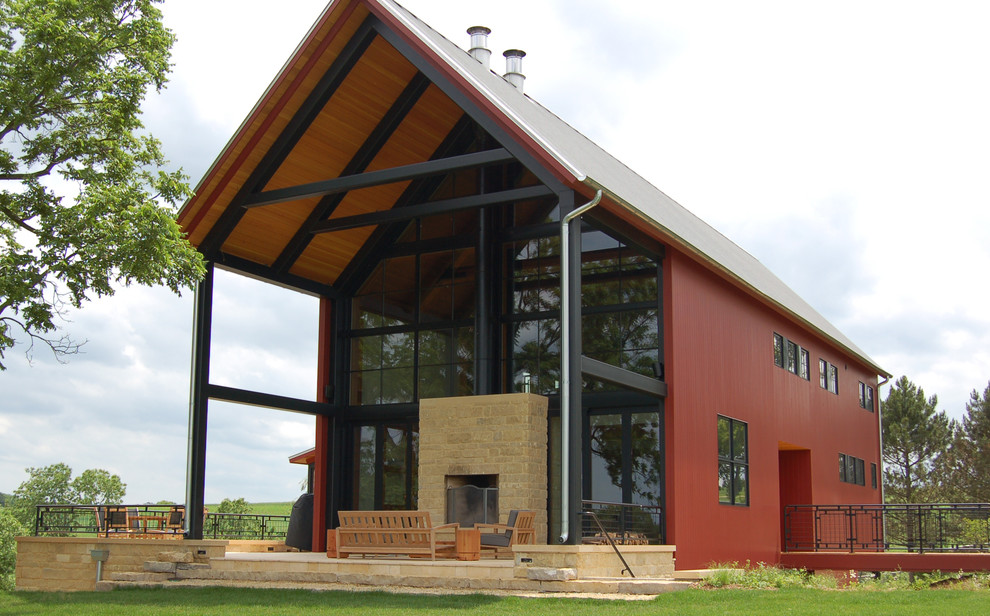 Immagine della villa grande rossa country a due piani con rivestimento in legno, tetto a capanna e copertura in metallo o lamiera