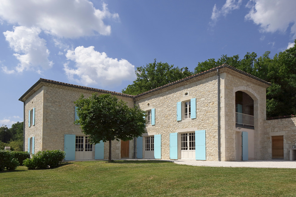 Aménagement d'une grande façade de maison beige méditerranéenne en pierre à un étage avec un toit plat.