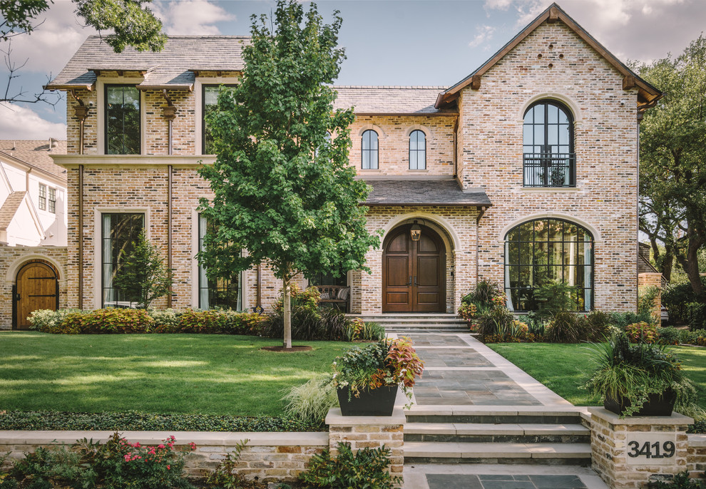 Example of a classic two-story brick house exterior design in Dallas with a shingle roof