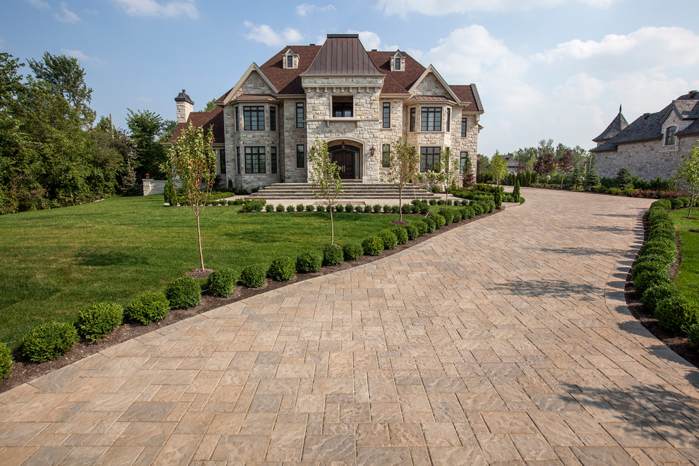 Large traditional beige two-story stone house exterior idea in Other with a hip roof and a shingle roof