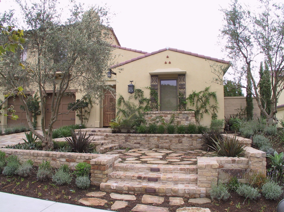 Diseño de fachada beige mediterránea de tamaño medio de dos plantas con revestimiento de adobe y tejado a dos aguas