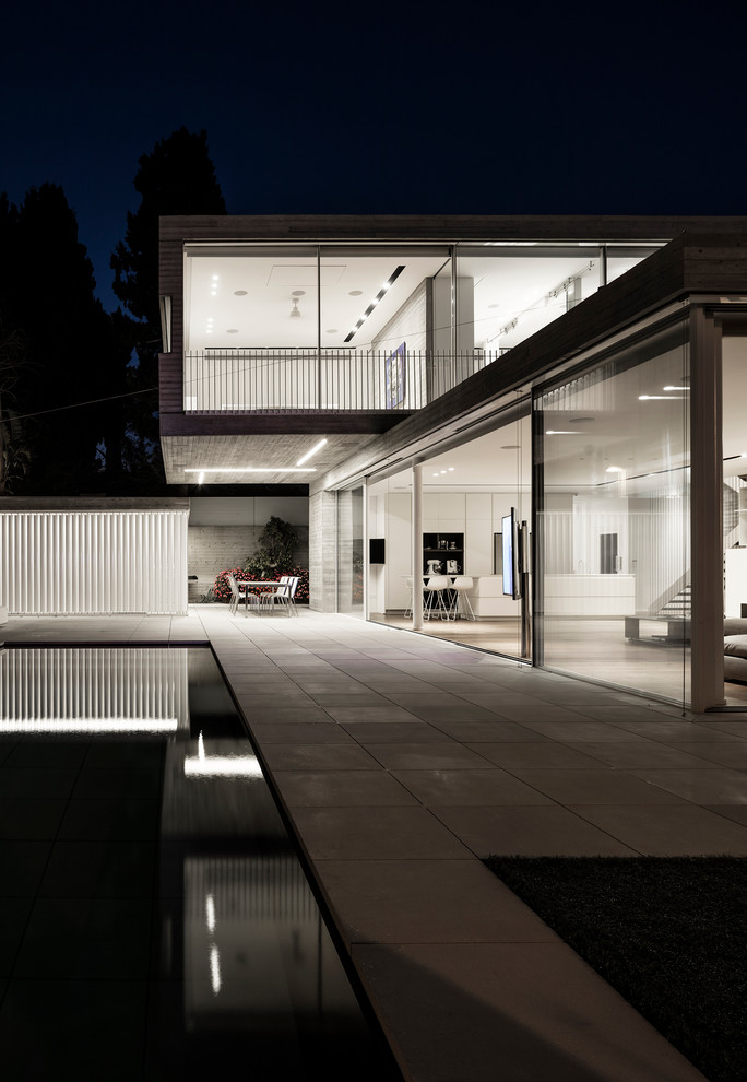 Réalisation d'une façade de maison grise minimaliste en béton à un étage avec un toit plat.