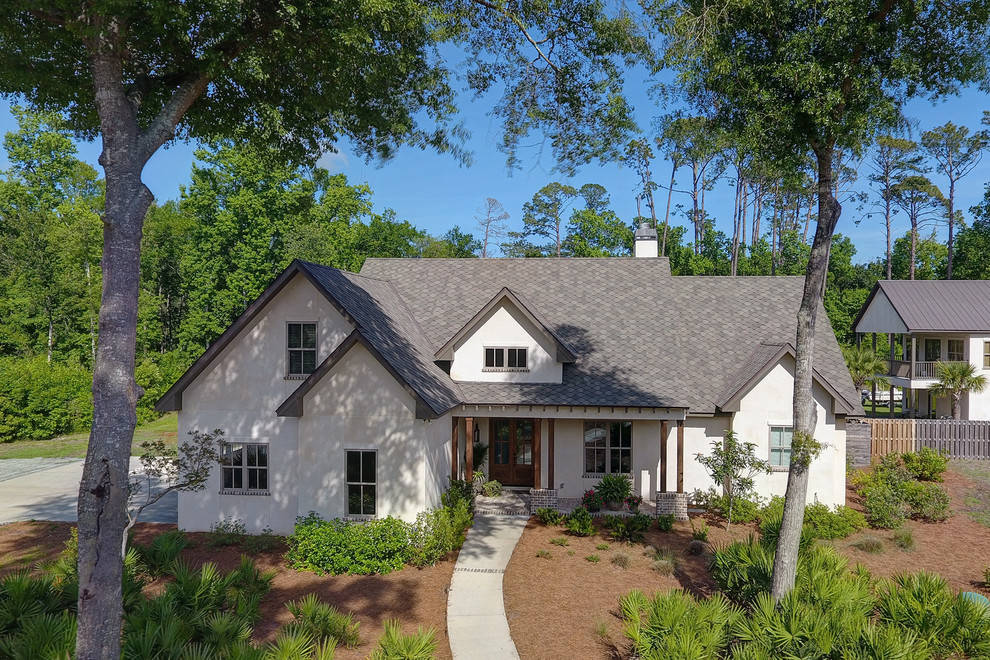 Large elegant white one-story stucco exterior home photo in Jacksonville with a shingle roof