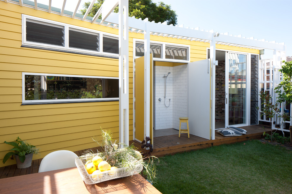 Идея дизайна: маленький, одноэтажный, желтый дом в стиле фьюжн с облицовкой из ЦСП и плоской крышей для на участке и в саду