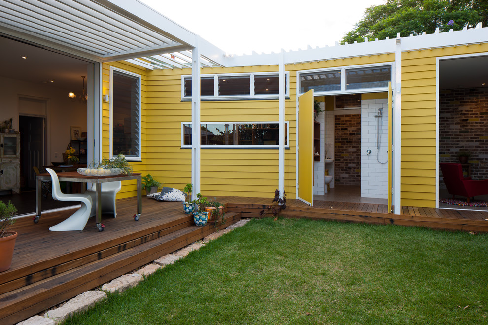 На фото: маленький, одноэтажный, деревянный, желтый дом в стиле фьюжн с плоской крышей для на участке и в саду с