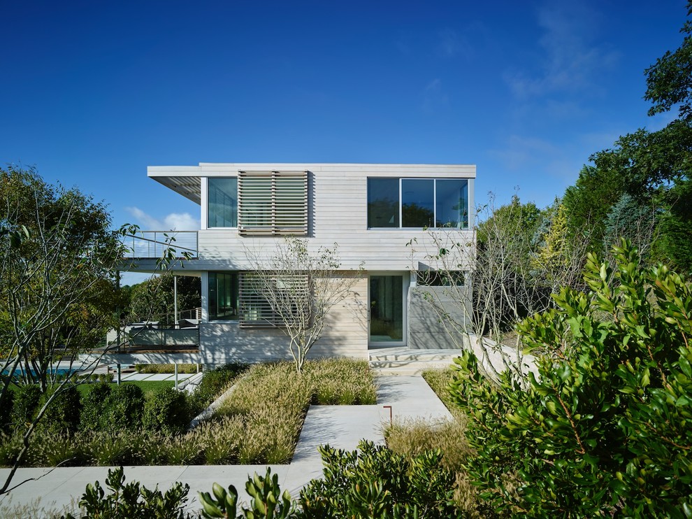 Modelo de fachada de casa beige costera de dos plantas con revestimientos combinados y tejado plano