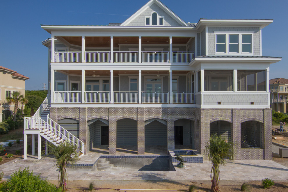 Cette photo montre une très grande façade de maison grise bord de mer en panneau de béton fibré à deux étages et plus avec un toit à deux pans et un toit en métal.