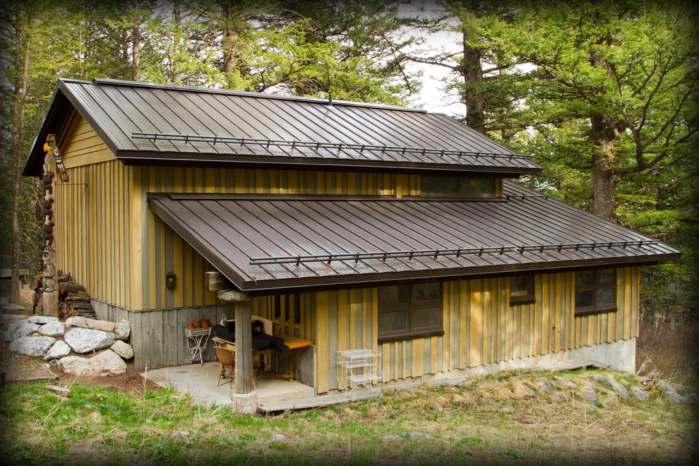 Ejemplo de fachada de casa beige rústica de tamaño medio de dos plantas con tejado a dos aguas y tejado de metal