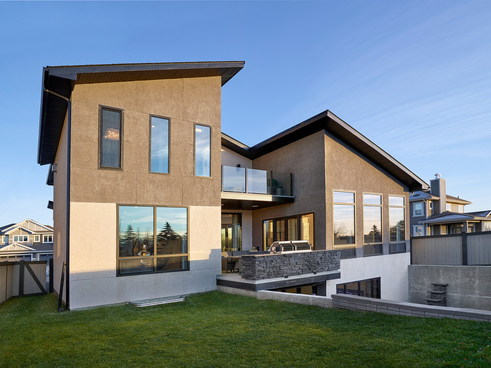 Cette photo montre une grande façade de maison grise tendance en stuc à un étage.