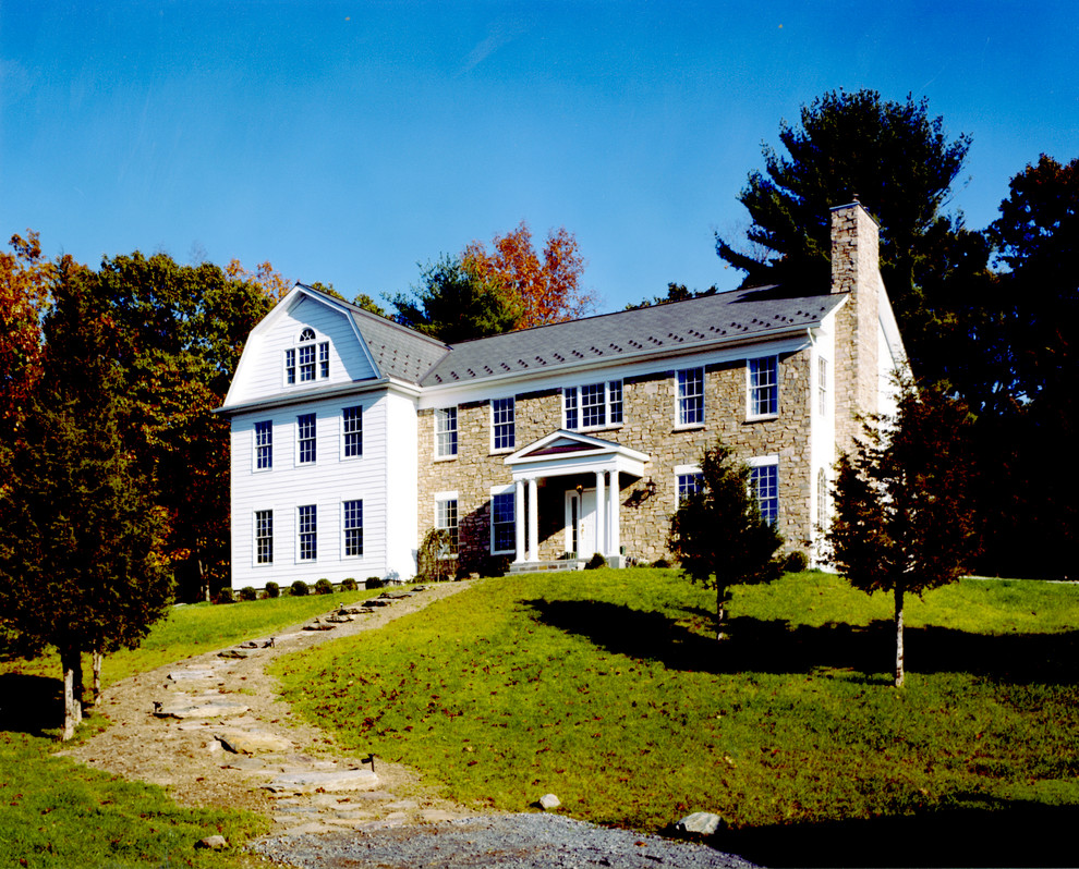 Inspiration for a large timeless white three-story stone exterior home remodel in New York with a gambrel roof