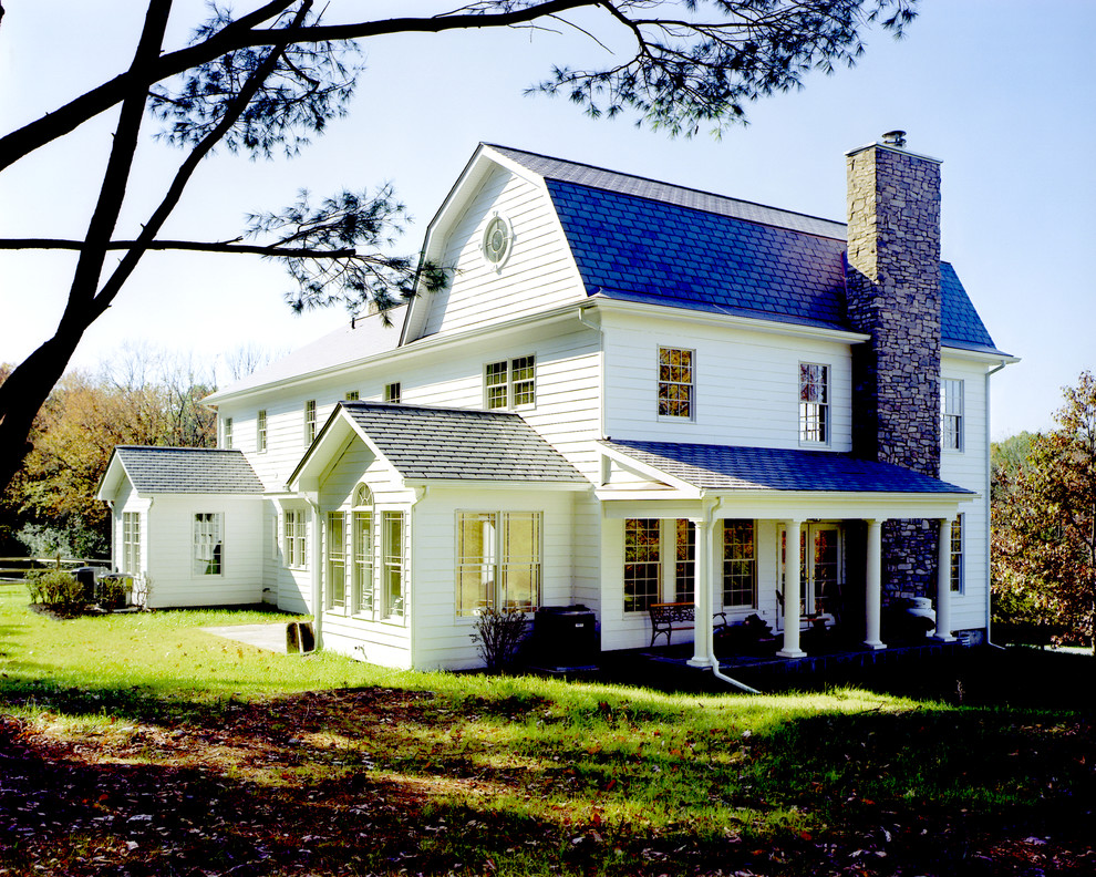 Example of a large classic white three-story stone exterior home design in New York with a gambrel roof