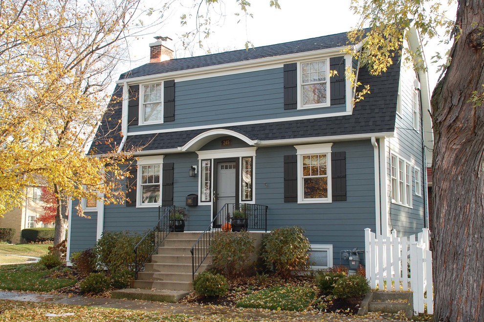 Modelo de fachada de casa azul clásica de tamaño medio de dos plantas con revestimiento de aglomerado de cemento, tejado a dos aguas y tejado de teja de madera