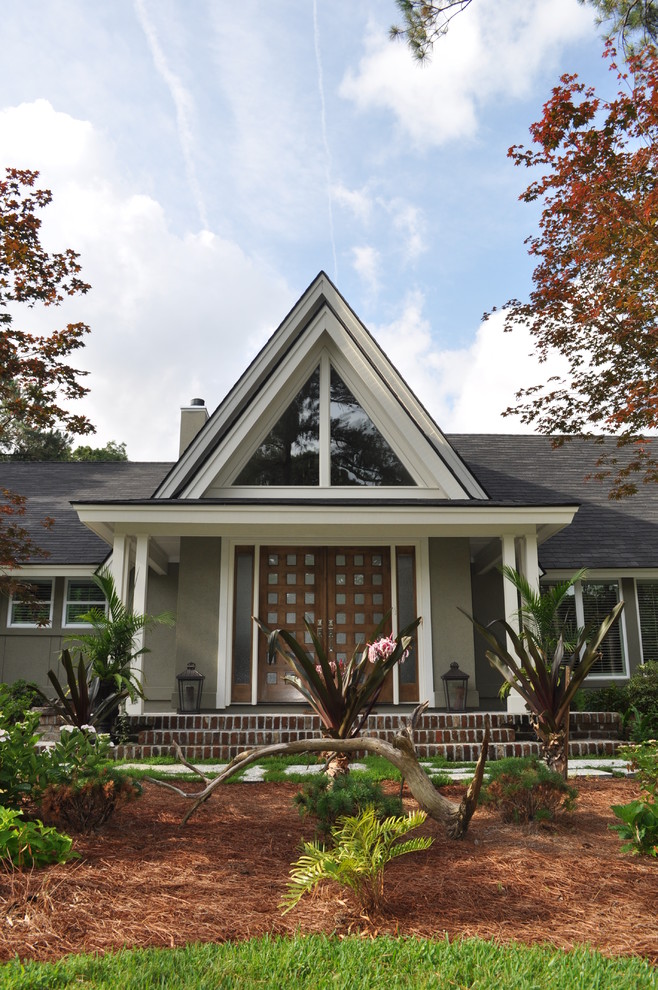 Cette photo montre une façade de maison grise exotique en stuc de taille moyenne et de plain-pied avec un toit à deux pans.