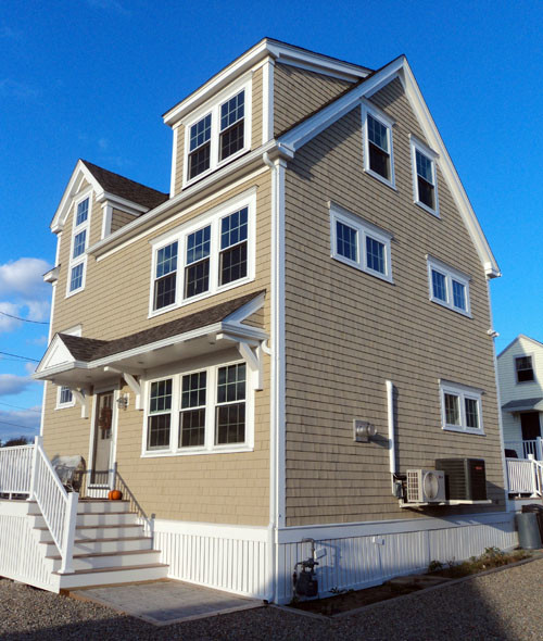 Cette photo montre une grande façade de maison beige bord de mer à deux étages et plus avec un revêtement mixte et un toit en shingle.