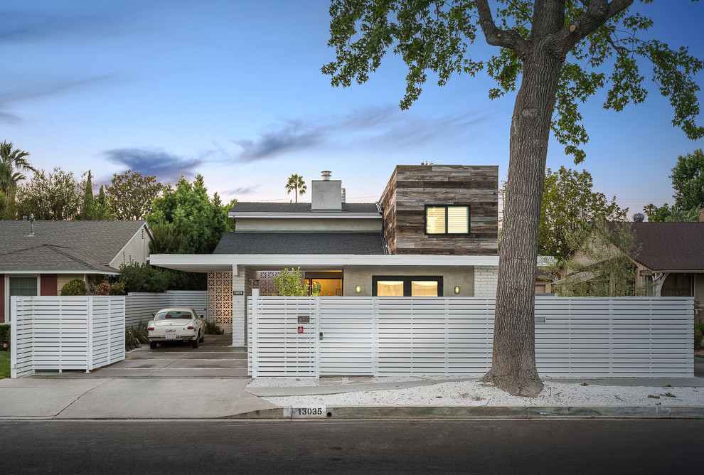 Réalisation d'une façade de maison multicolore vintage de taille moyenne et à un étage avec un revêtement mixte et un toit en appentis.